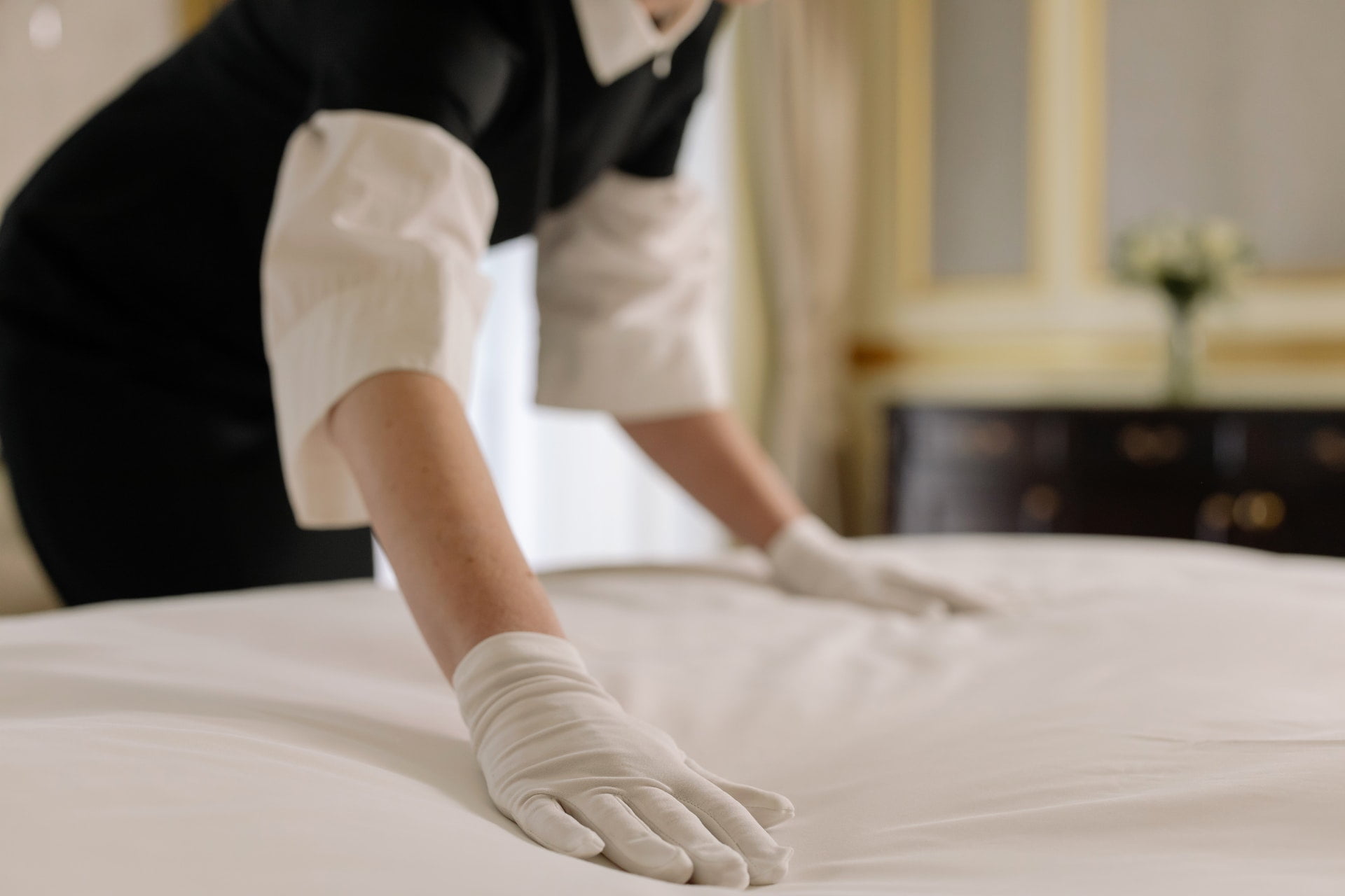 a cleaner wearing a white gloves cleaning the bed