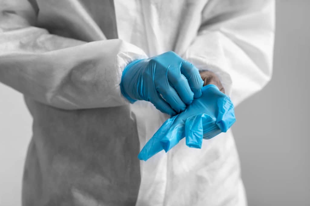 a person wearing a personal protective equipment and a blue disposable gloves