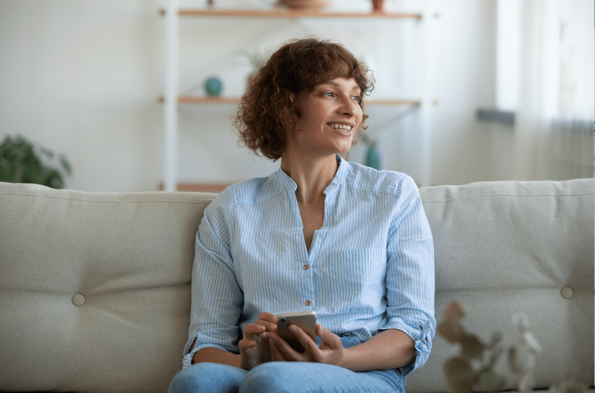 Smiling woman looks out holding a phone in her hands